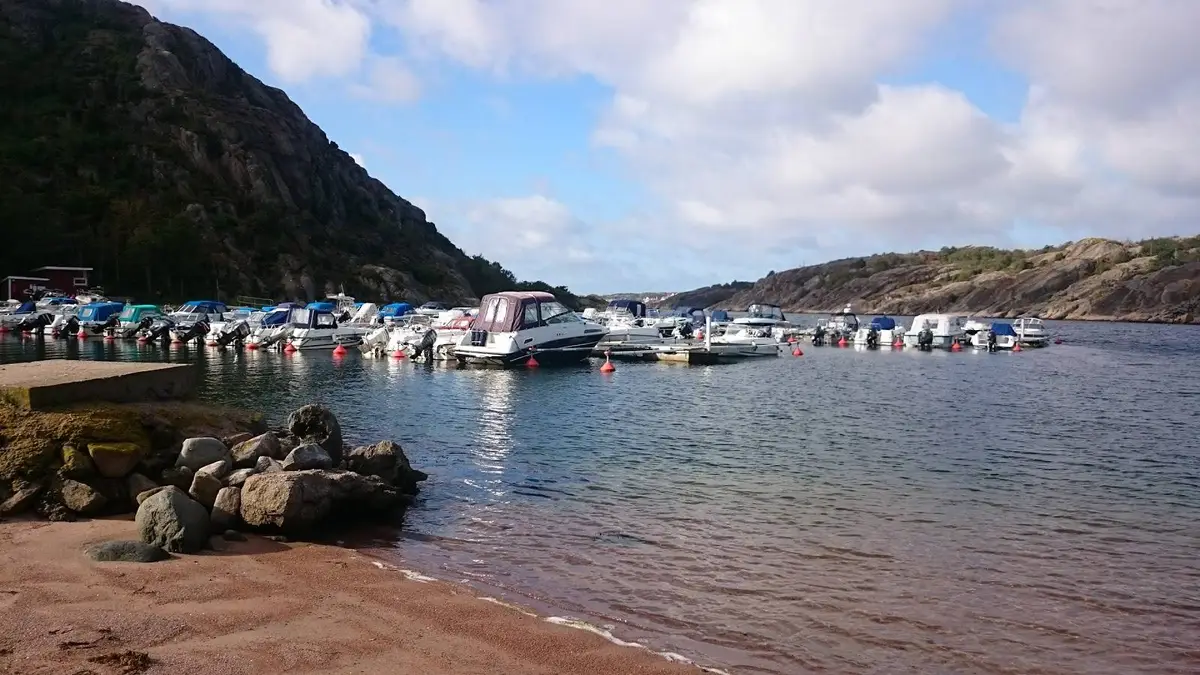 En motorbåt ligger förtöjd vid en brygga på Örns camping, med en rofylld sjö och skogklädda stränder i bakgrunden.
