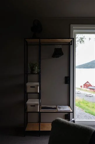 Ett modernt och stilrent inrett rum på Skuleberget Havscamping, med trägolv, hyllor och lampor som skapar en varm atmosfär.