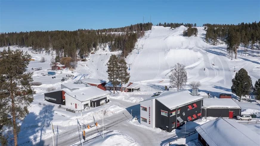 En snötäckt campingplats i Skellefteå, med vinterlandskap och stugor omgivna av glaciära landformer och frostiga backar.
