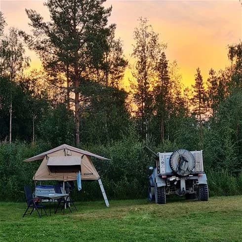 En campingplats vid Sonfjällscampen med uppställda tält och ett canopyskydd, omgiven av natur.
