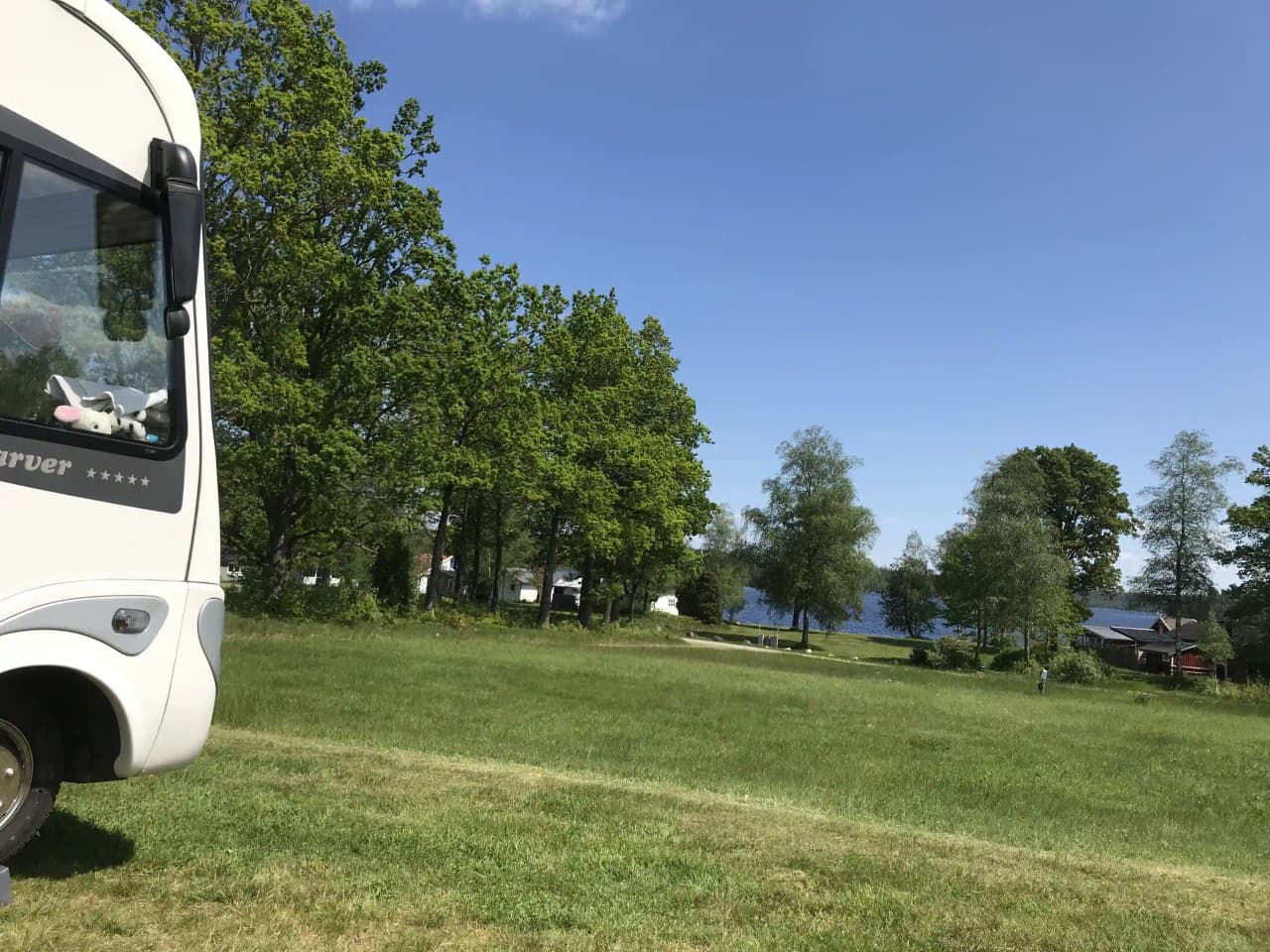En husvagn och en skåpbil står parkerade på en grön gräsmatta vid Bexet Camping.