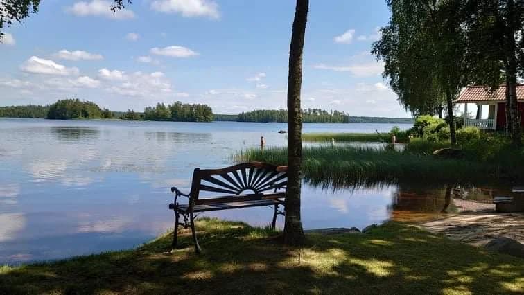 En naturskön vy över en stilla sjö vid Bexet Camping, omgiven av frodig grönska och speglingar i vattnet.