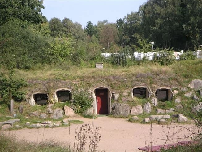 En naturskön campingplats vid en grottöppning, omgiven av lummig skog och grönska.