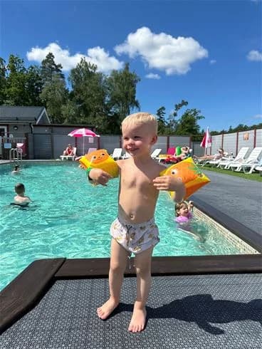 En somrig campingmiljö vid Stenrösets camping i Trollhättan, där barn leker och har roligt i en pool.