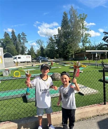 En grupp barn leker på Stenrösets camping i Trollhättan. En park som erbjuder olika fritidsaktiviteter, inklusive racketsporter, vilket skapar en rolig och avkopplande semestermiljö.