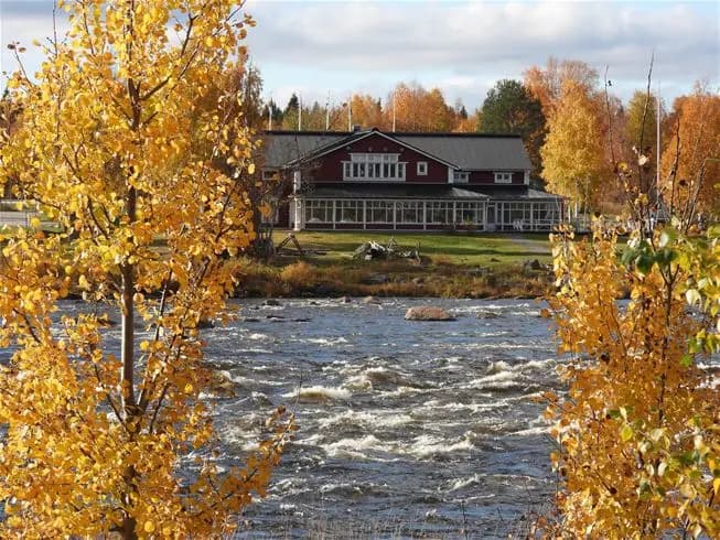 En flodlandskap vid Kukkolaforsen i hösttid, med spegelblanka vattendrag omgivna av kvardröjande höstfärger och våtmark.