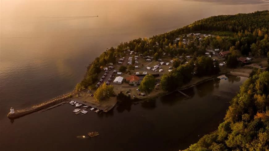 Vy över en naturskön vattenled omgiven av frodig grönska och träd vid Kinnekulle camping & stugby.