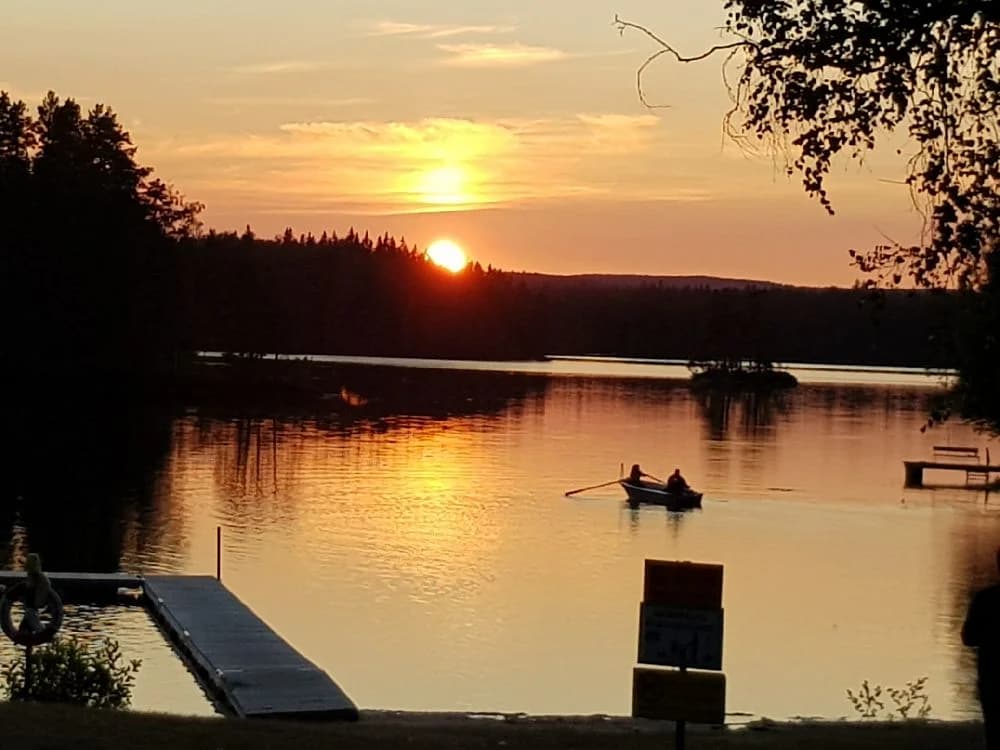 En vacker solnedgång vid vattnet vid Liens Camping, där himlen färgas i mjuka kvällsfärger och vattnet ligger stilla.