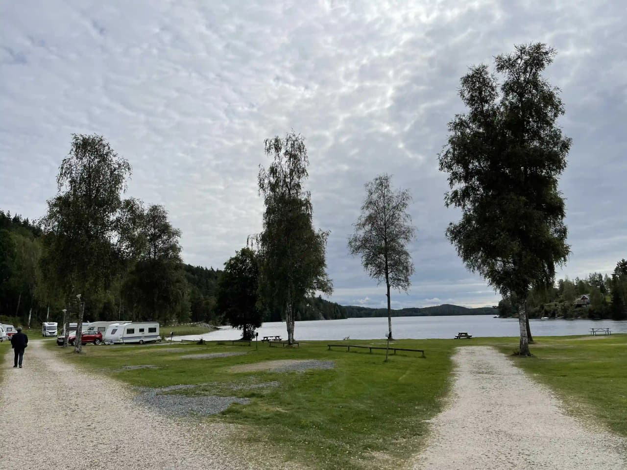 En grönskande campingplats vid Ragnerudssjön med välklippta gräsmattor, omgiven av frodig natur och rofyllda vatten.