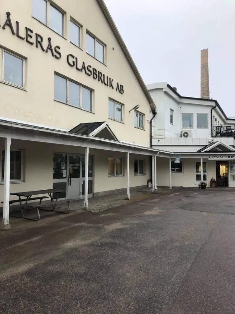 Alt-text: "En exklusiv parkeringsplats vid Målerås Glasbruk, fylld med olika typer av personbilar, inklusive lyxbilar och SUV:ar."