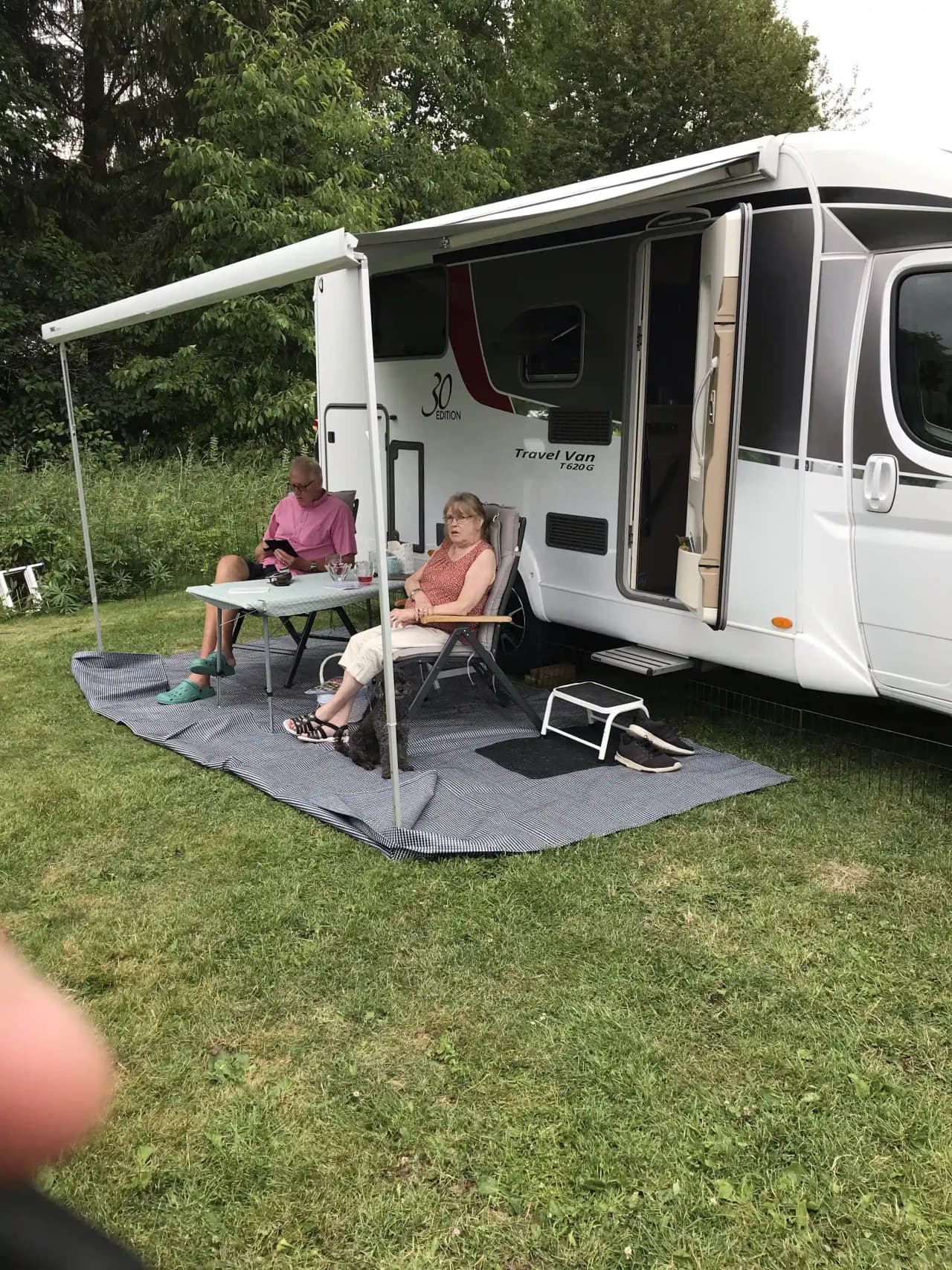 En solig dag på Harge Bad & Camping med husvagnar och bilar parkerade på gräsplanen. Campingstolar står uppställda vid sidan, redo för avkopplande stunder i naturen.