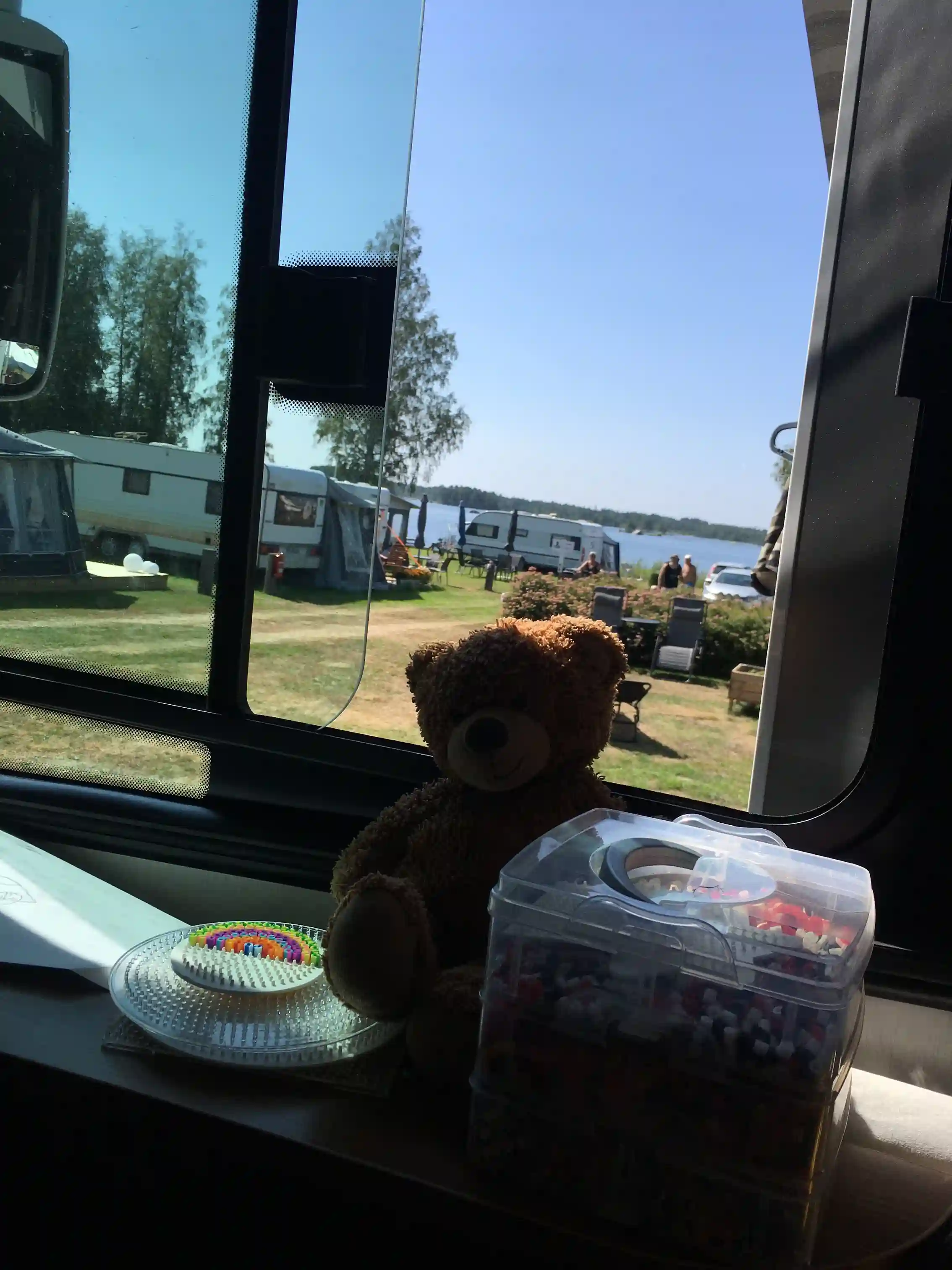 En morgonbild från en bil vid Högbacka Camping, sedd genom vindrutan och sidospegeln, vilket ger en känsla av att vara på en roadtrip.