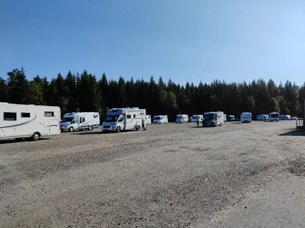 En parkeringsplats vid Ullared camping med flera parkerade fordon, inklusive bilar och husbilar.