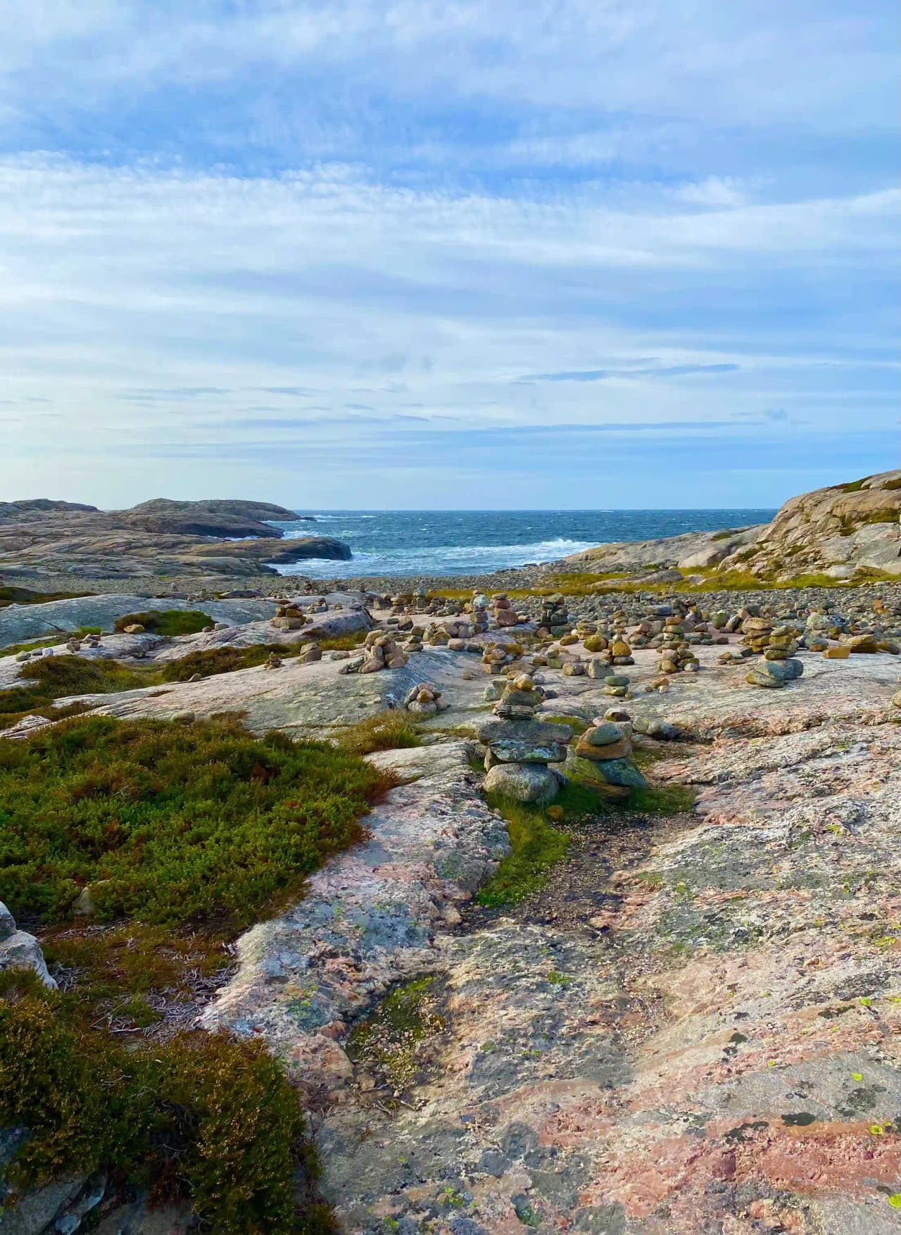 En karg kustlinje med blått hav och klippformationer, representerar Saltviks campings vilda och natursköna miljö.