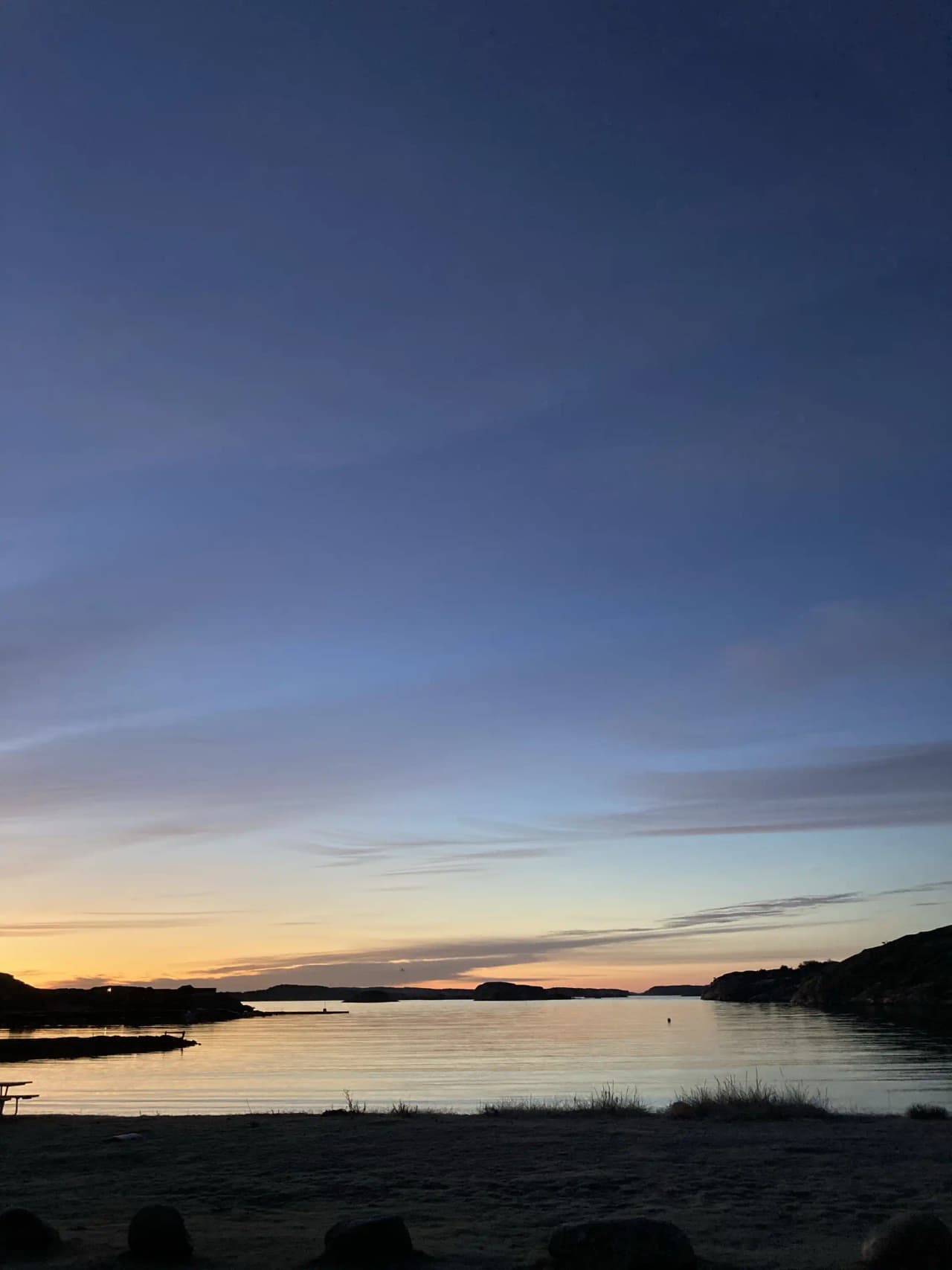 En vacker vy över Saltviks camping vid solnedgången där himlen speglas i det stilla vattnet.