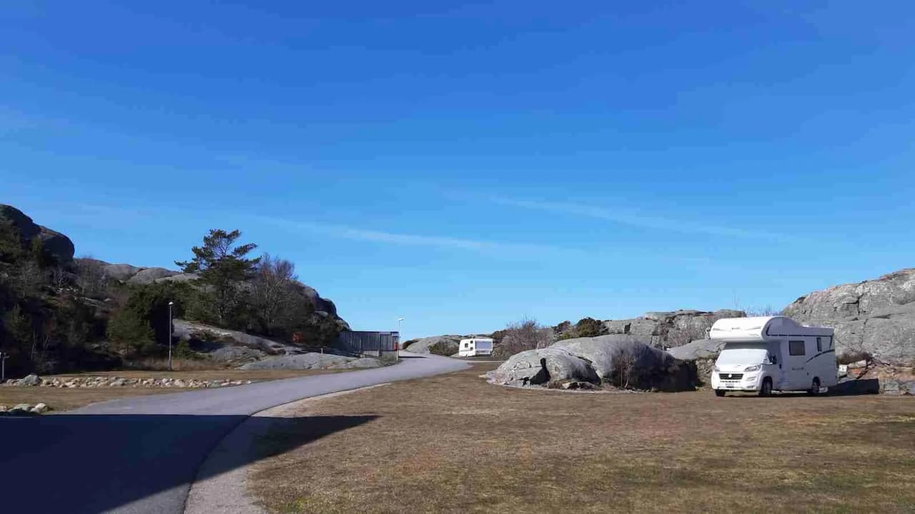 En husbil står parkerad nära en kuperad terräng vid Hav & Logi Skärhamn, med en scenisk utsikt över naturlandskapet i bakgrunden.