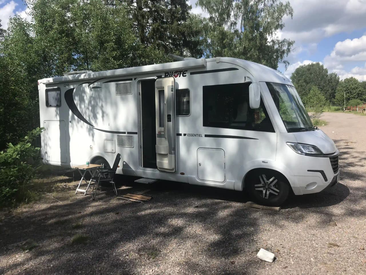 En rad av husvagnar och mobila hem uppställda på ett gräsområde vid Vimmerby Camping - Nossenbaden, omgivna av grönska och träd i bakgrunden.