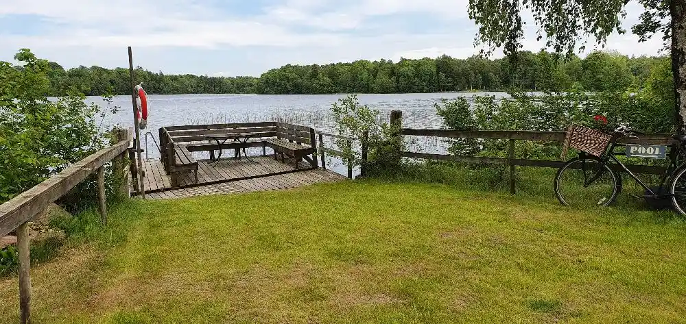 En stilla sjö omgiven av frodig grönska, med vattnet som speglar den naturliga miljön runt omkring.