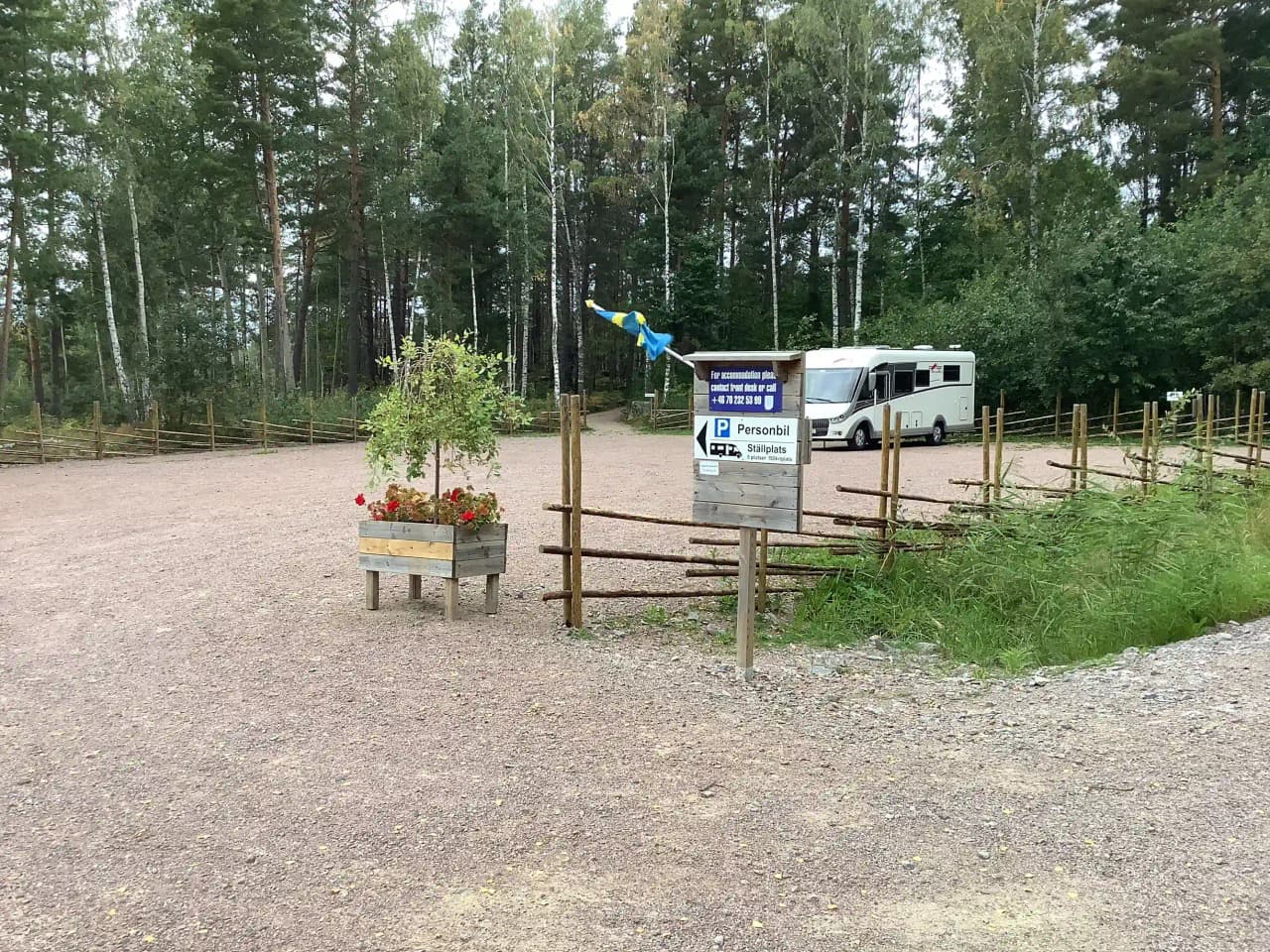 En grusväg leder in i Hätte Camping, omgiven av grönskande natur och träd, som skapar en fridfull och inbjudande atmosfär för besökare.