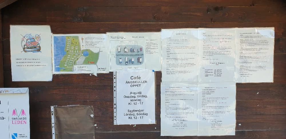 En anslagstavla med handskriven information och pappersmaterial, omgiven av träpanel, belägen vid Målsånna Camping Park.
