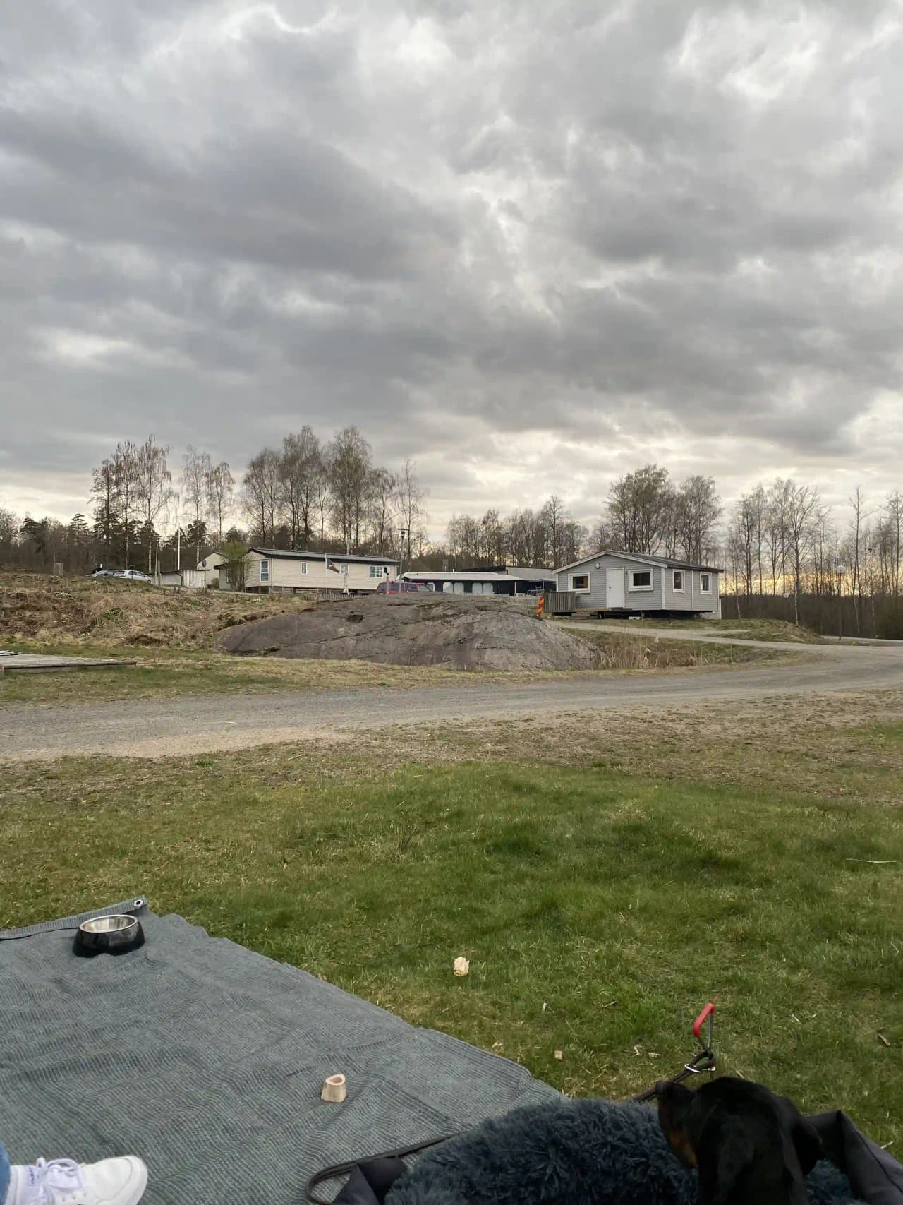 En vidsträckt campingplats omgiven av öppna fält under en himmel med molnformationer och inslag av cumulusmoln.