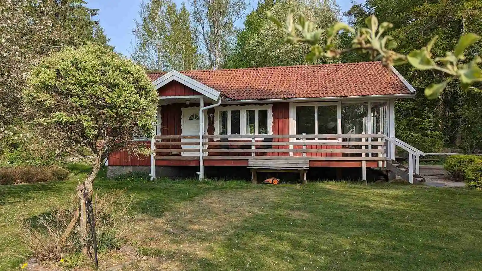En lantlig stuga med träfasad och tak, omgiven av en grön gräsmatta, vid Hjorthalan Camping.