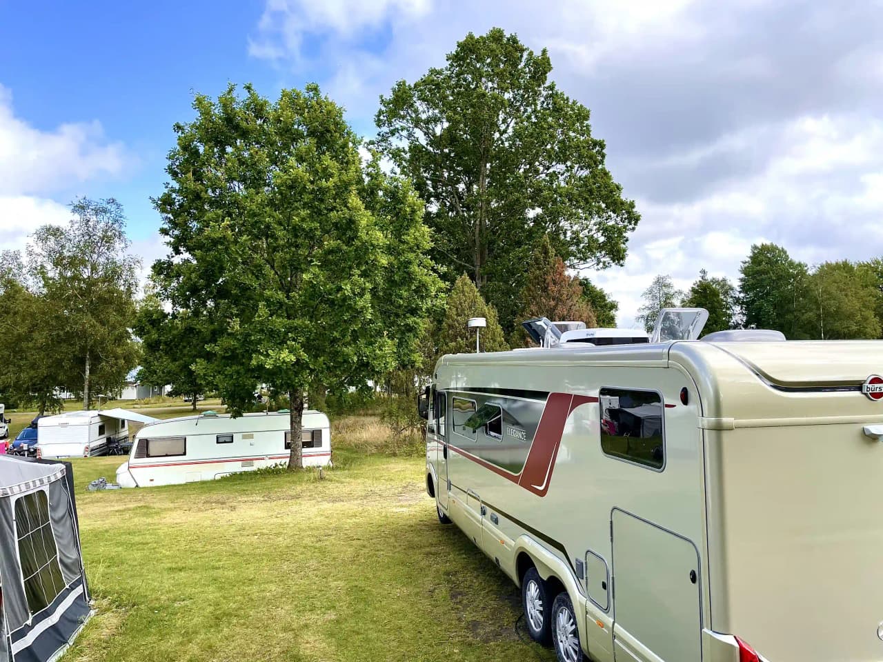 Bild av en husvagn parkerad på Bexet Camping, omgiven av grönska.