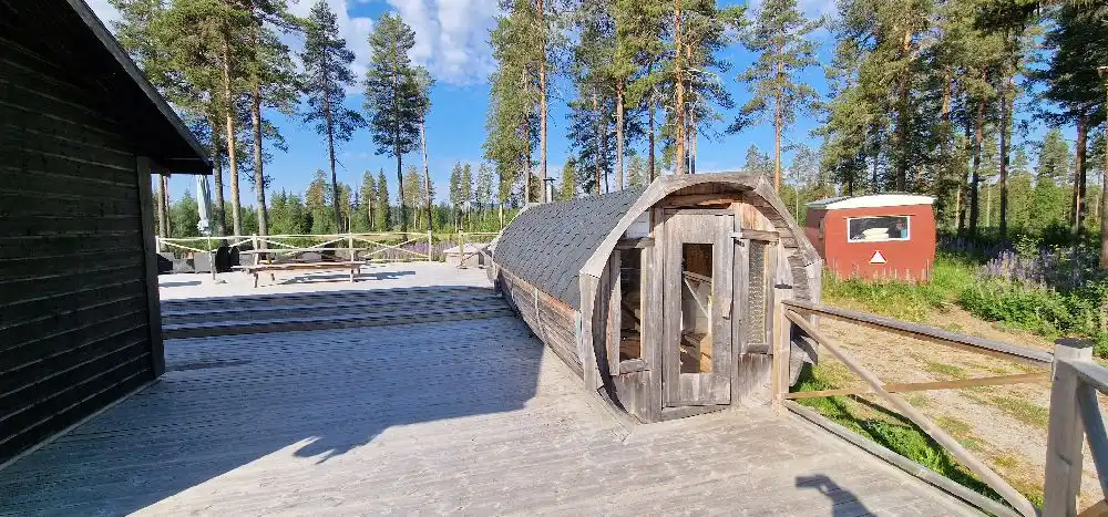 En naturskön campingplats vid Bjurholms camping med ett trästaket och ett plank som ramar in en del av området, vilket ger en rustik och fridfull atmosfär.