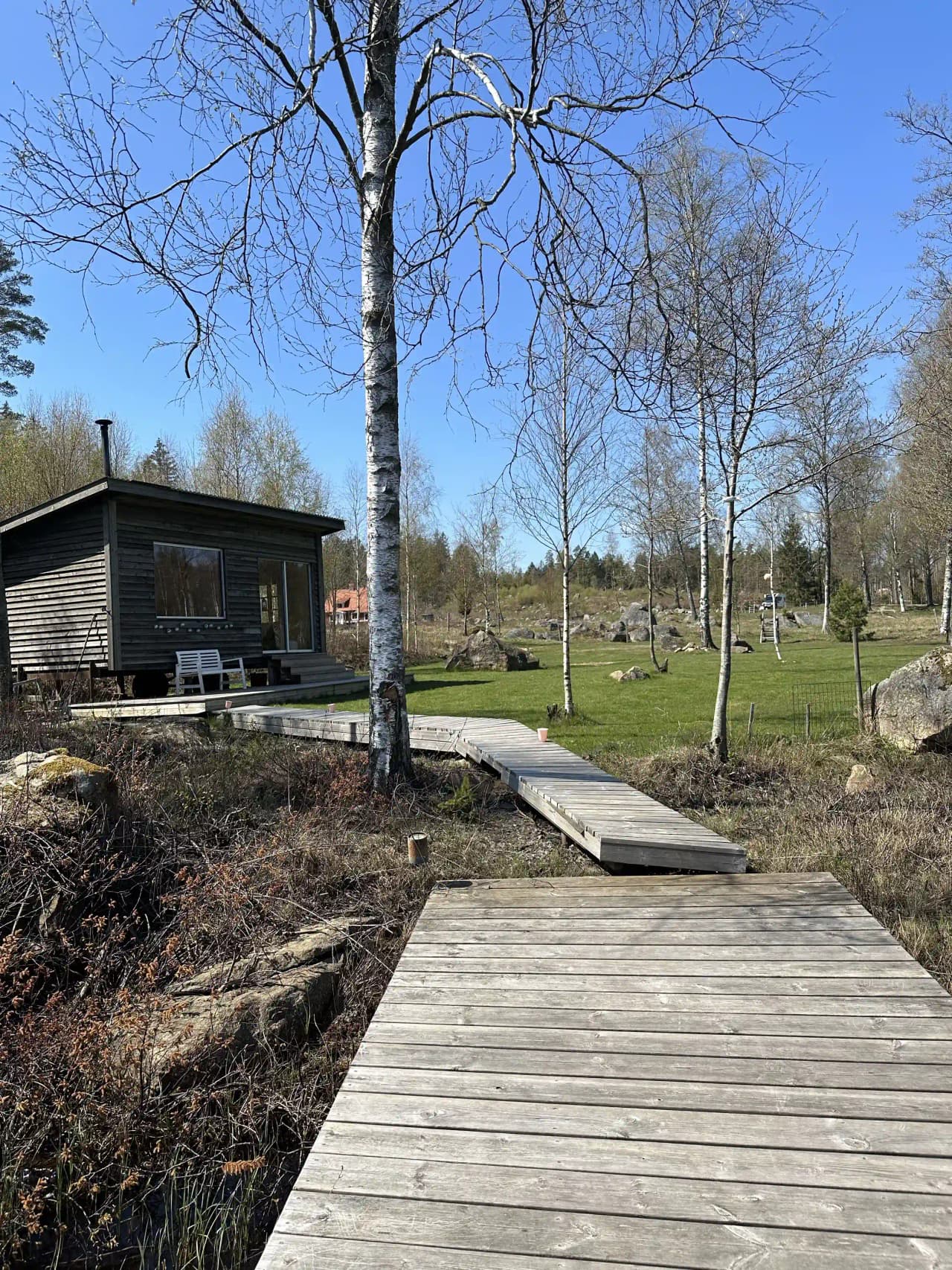 Träspång som slingrar sig genom ett frodigt våtmarksområde vid Stjernkvist's Hunshult, omgiven av grönskande natur och träd.