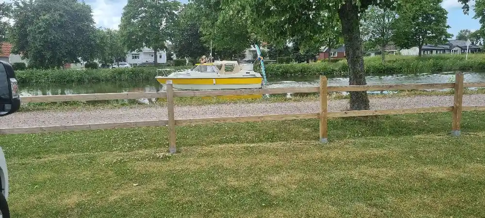 En grönskande campingplats med en välskött gräsmatta och gångvägar. Ett staket omger området, som ger en känsla av öppet och inbjudande allmänt utrymme.