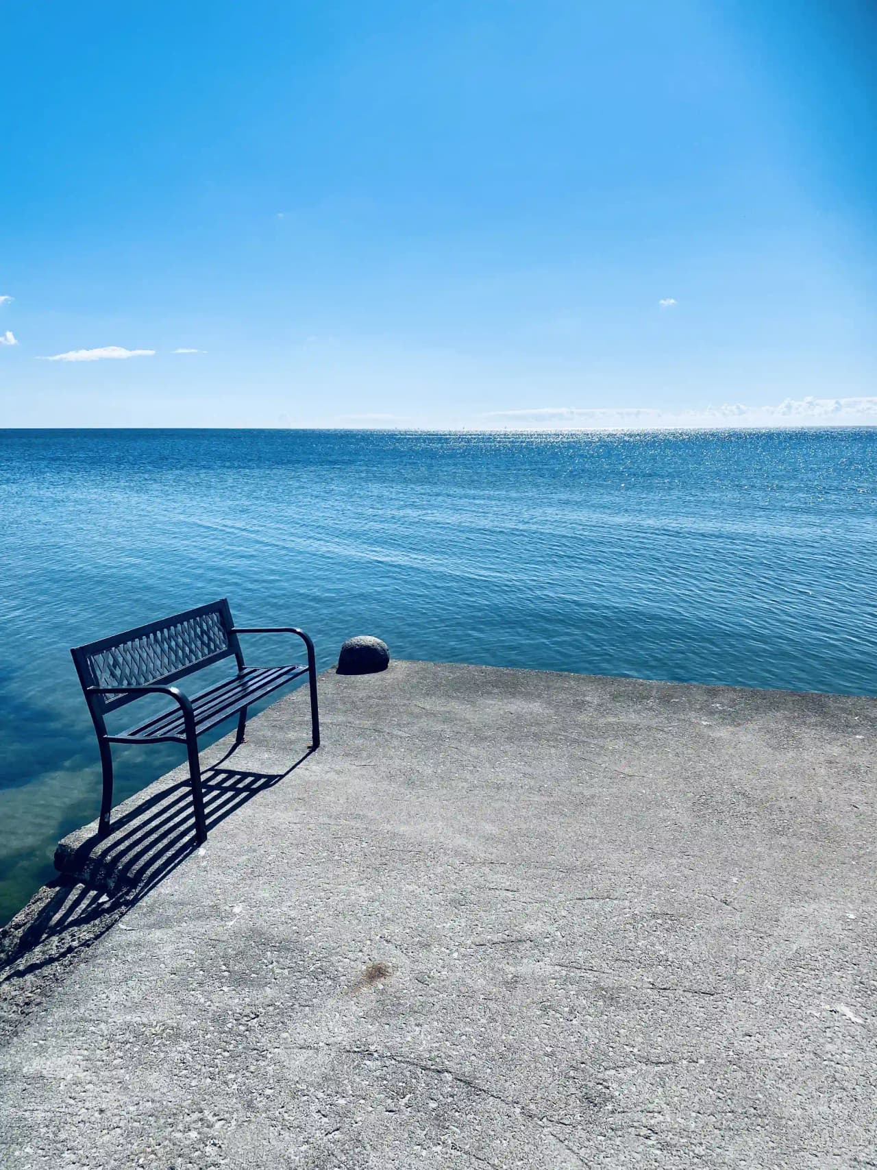 En somrig dag vid Björknäs camping med blått krusigt vatten under en klarblå himmel i bakgrunden.