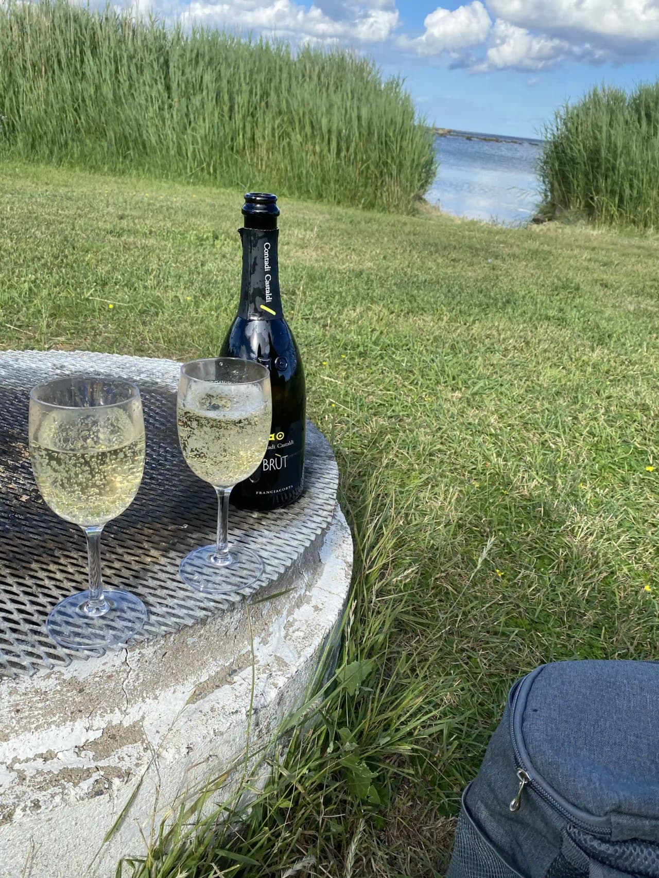 En campingplats med ett fokus på avslappning och gemenskap, där ett dukat bord med alkoholhaltiga drycker, vinglas och champagneglas visas upp som en del av upplevelsen.