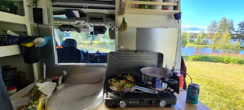 En husbil och en husvagn parkerade på Fredrika Camping, omgiven av grönska.