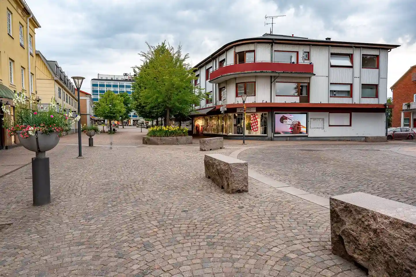 En bild av Värnamo camping som visar en asfalterad väg omgiven av grönskande omgivningar och campingfaciliteter, i en småstads- och stadsnära miljö med trottoarer och stenlagda ytor.