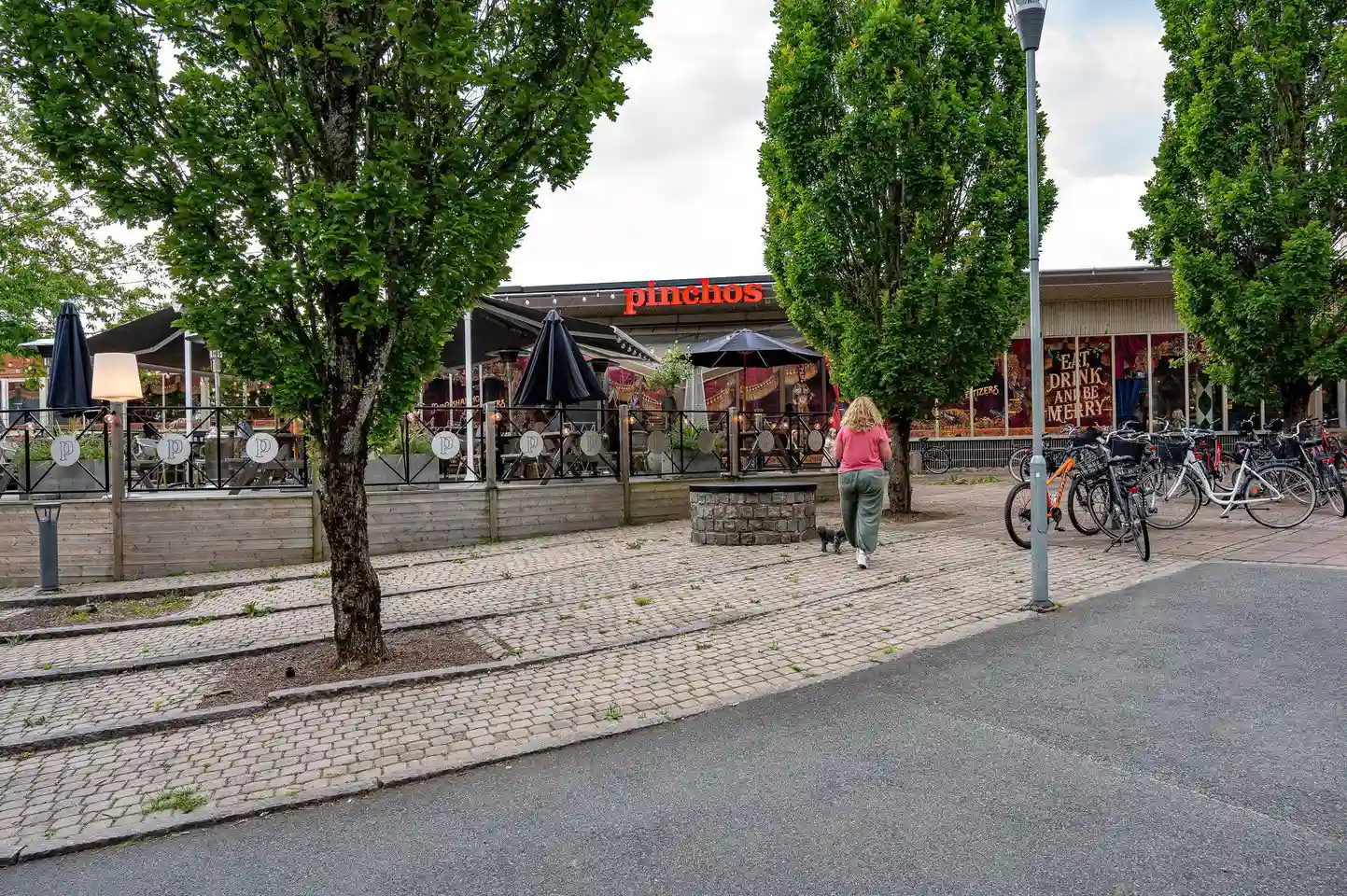 En utomhusmiljö på Värnamo camping med bord och stolar under parasoller, avsedd för besökare att koppla av och äta vid.