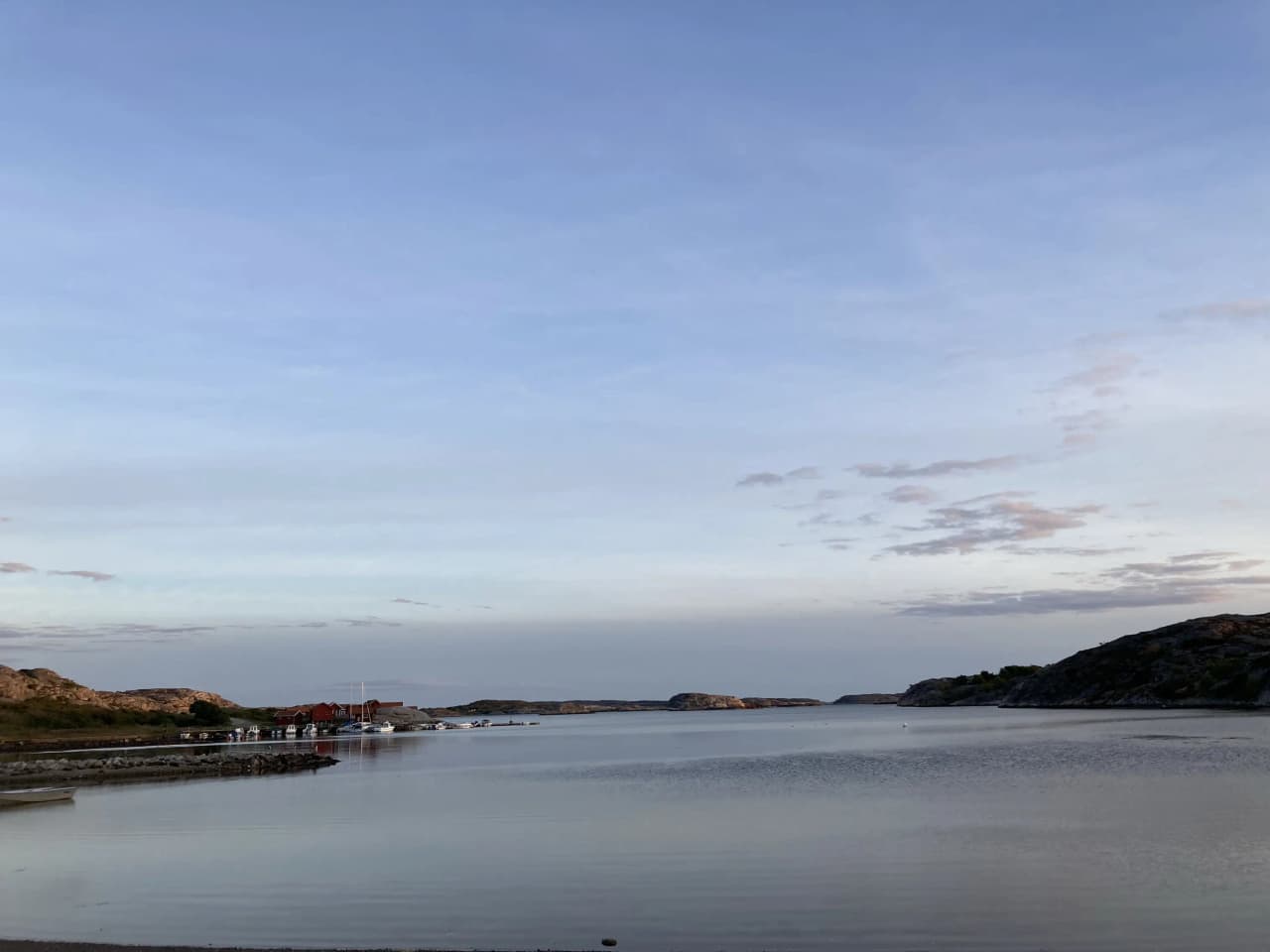 Vy över Saltviks camping med en klarblå himmel och moln, kustlinje och öppet vatten i förgrunden.