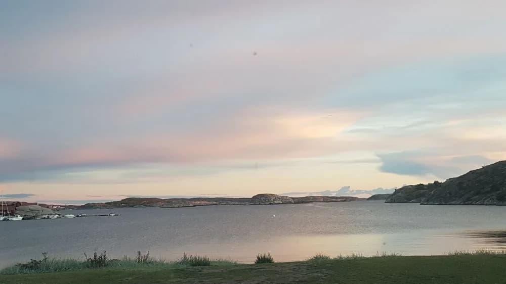 En bild av det natursköna kustlandskapet vid Saltviks Camping med klar himmel, vidsträckt vatten och en horisont som delar hav och land.