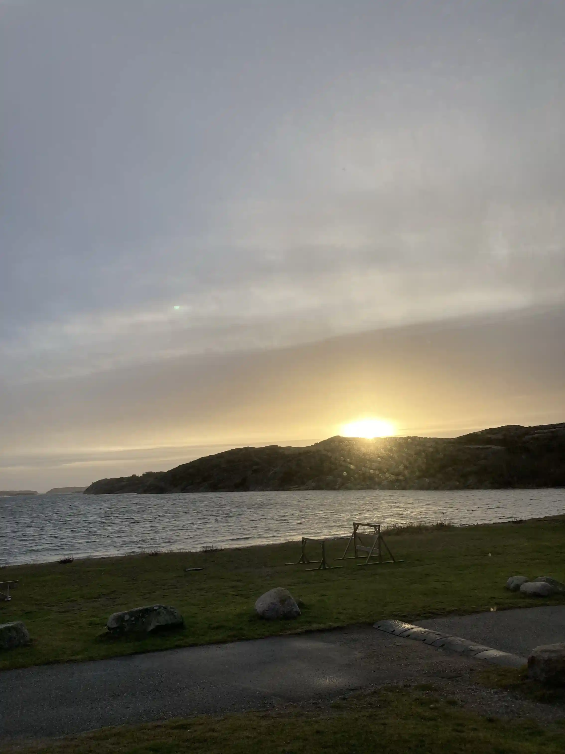En solnedgång över en kustlinje vid Saltviks camping, med en pittoresk himmel fylld av moln, horisonten syns där himmel möter vatten.