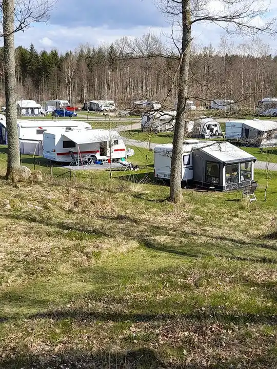 En grönskande campingplats i Våxtorp med gräs, träd och en husvagn i en lantlig miljö.
