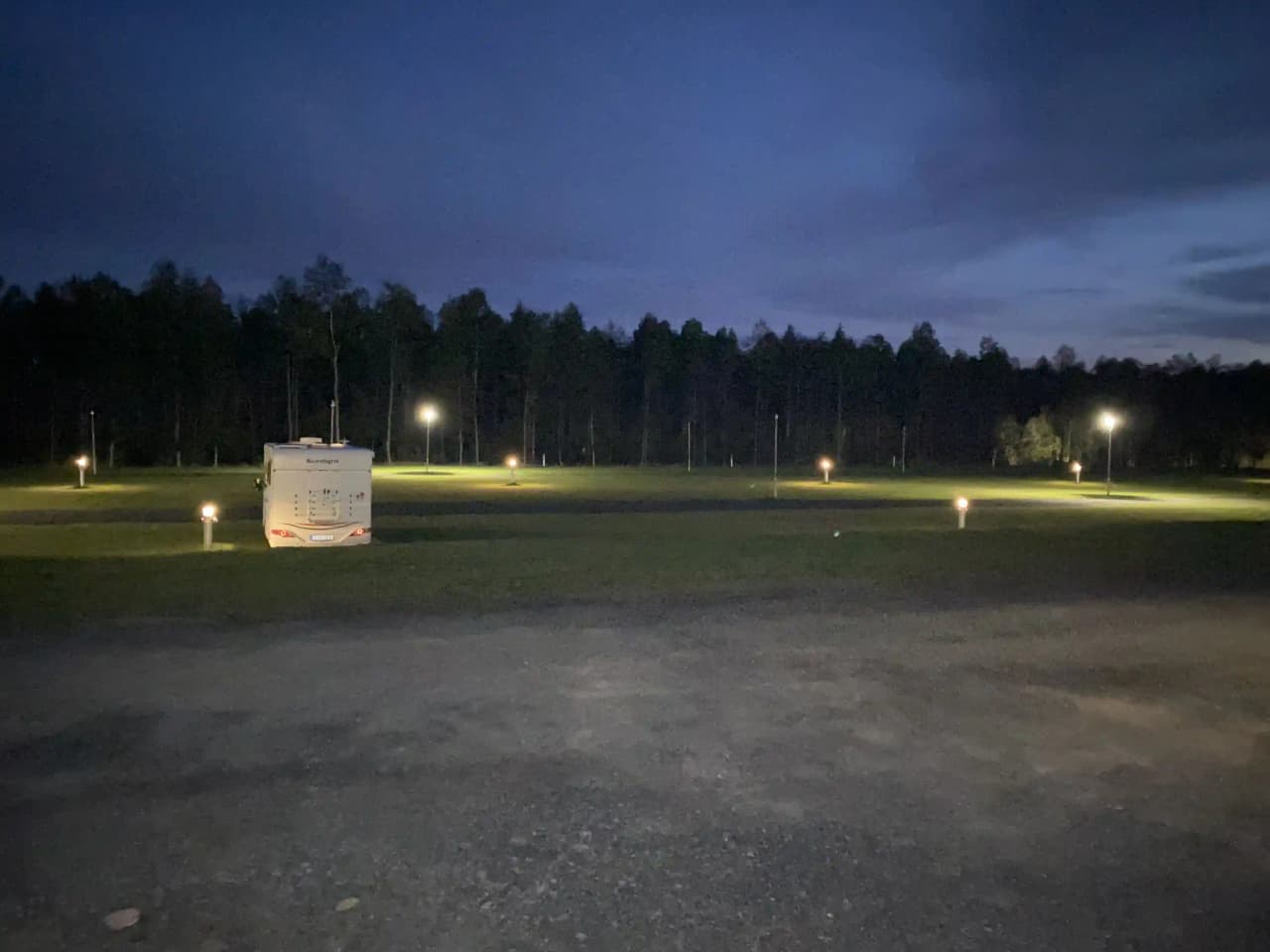 En nattlig scen vid Cape East med fokus på belysning och säkerhetslampor som lyser upp i mörkret, med ett inslag av lens flare från gatubelysningen.