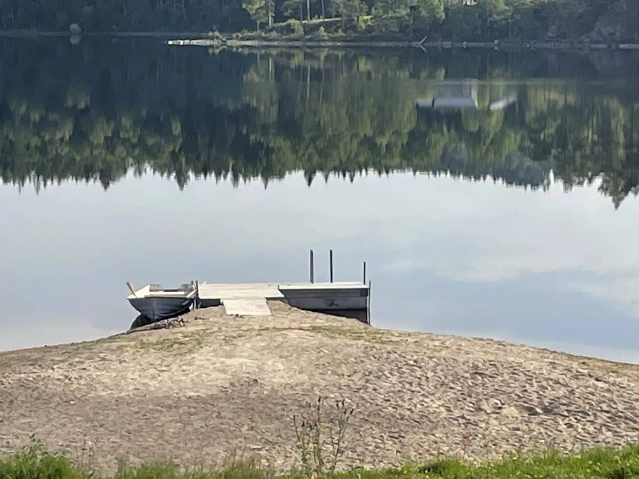 En pittoresk campingplats vid vattnet med brygga och omgivande grönska vid Gröna Backe Camping & Stugor.