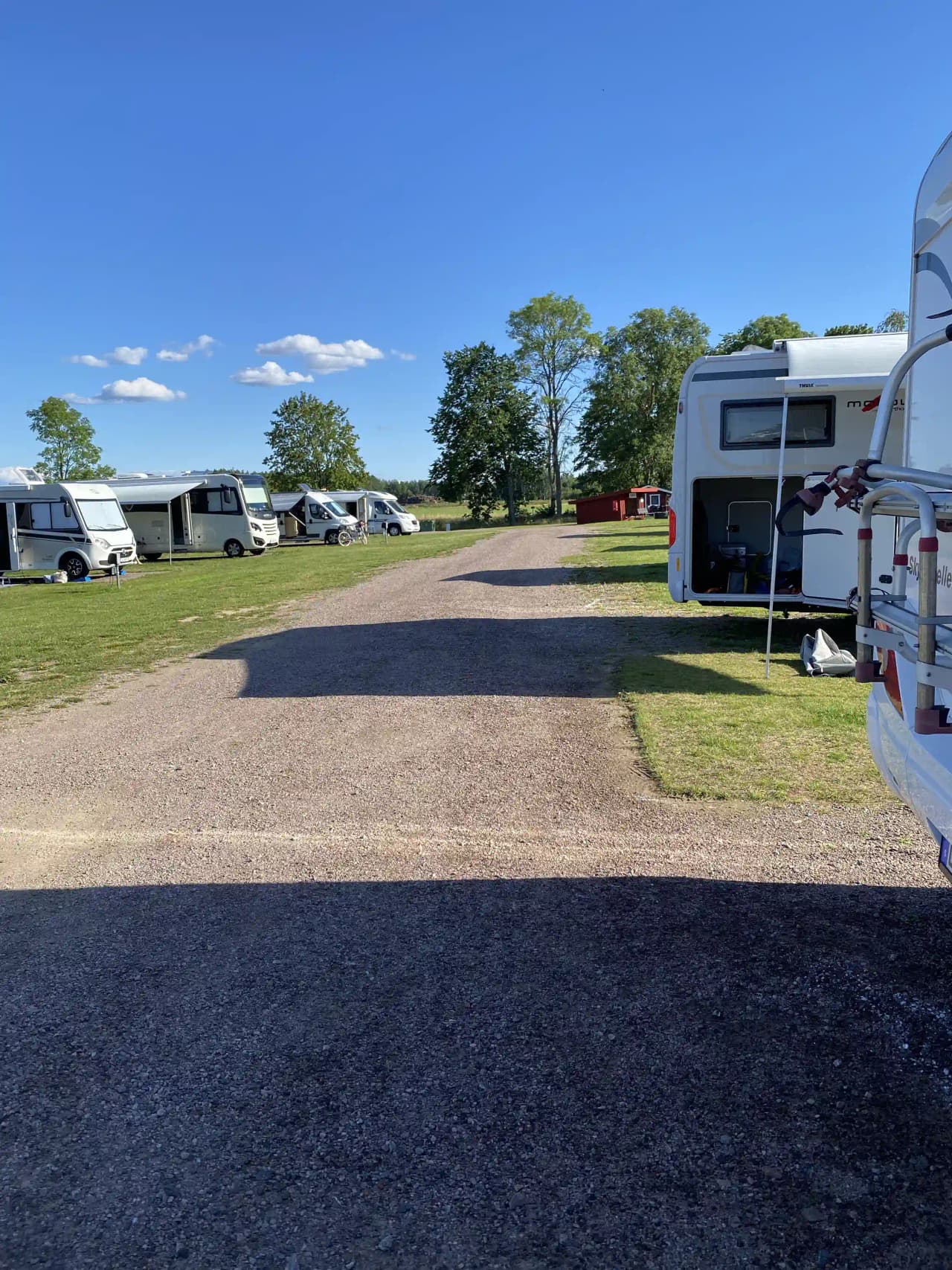 En parkeringsplats i Jonsboda med husbilar och husvagnar under en himmel med moln. En lastbil syns också på området.