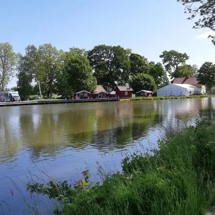 En naturskön miljö vid Jonsboda med vatten, omgivande träd och ett närliggande hus.