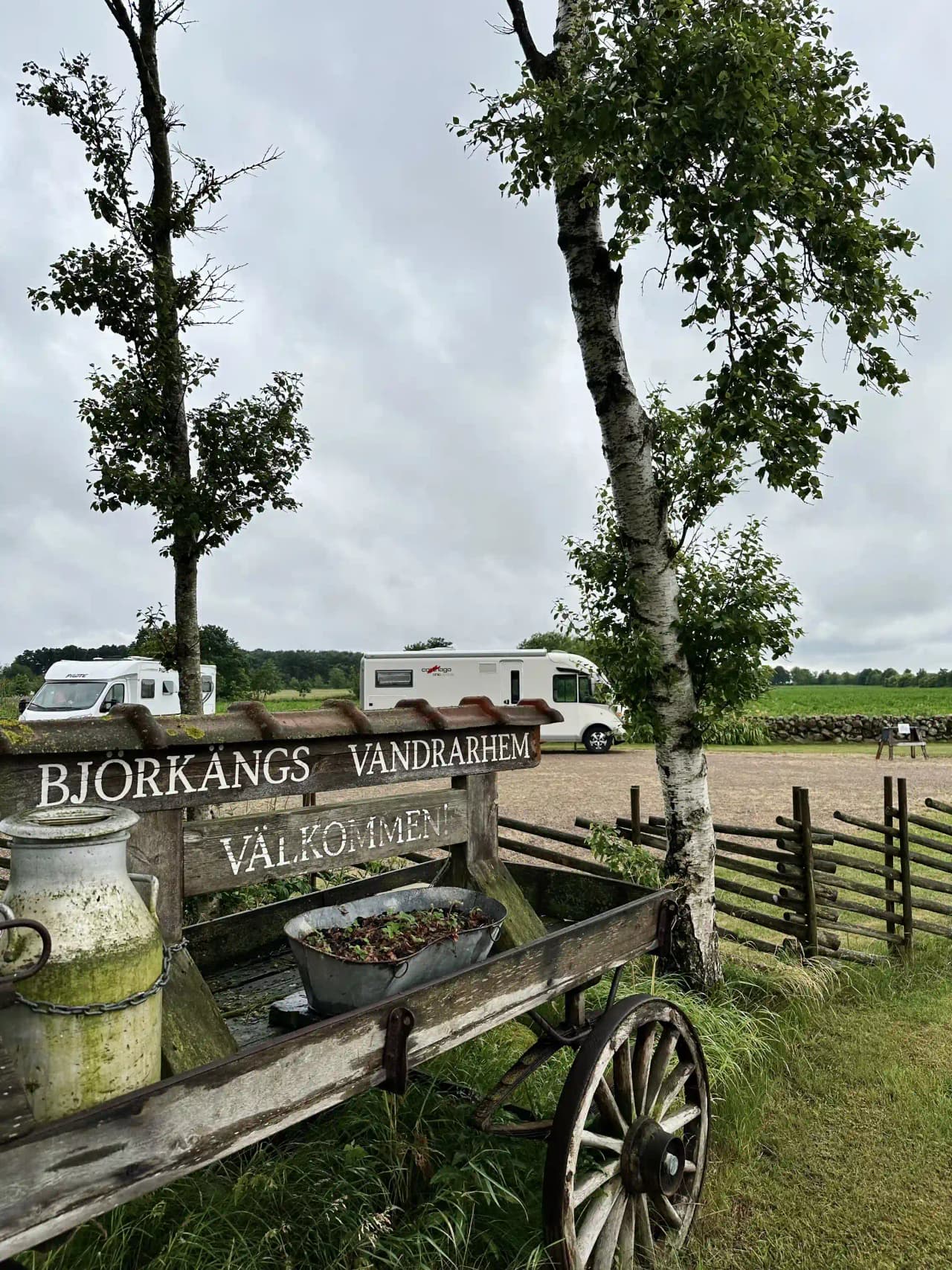 En gårdsplan med äldre vagnar och hjul, troligen vid Björkängs vandrarhem, med lantlig atmosfär och historisk charm.