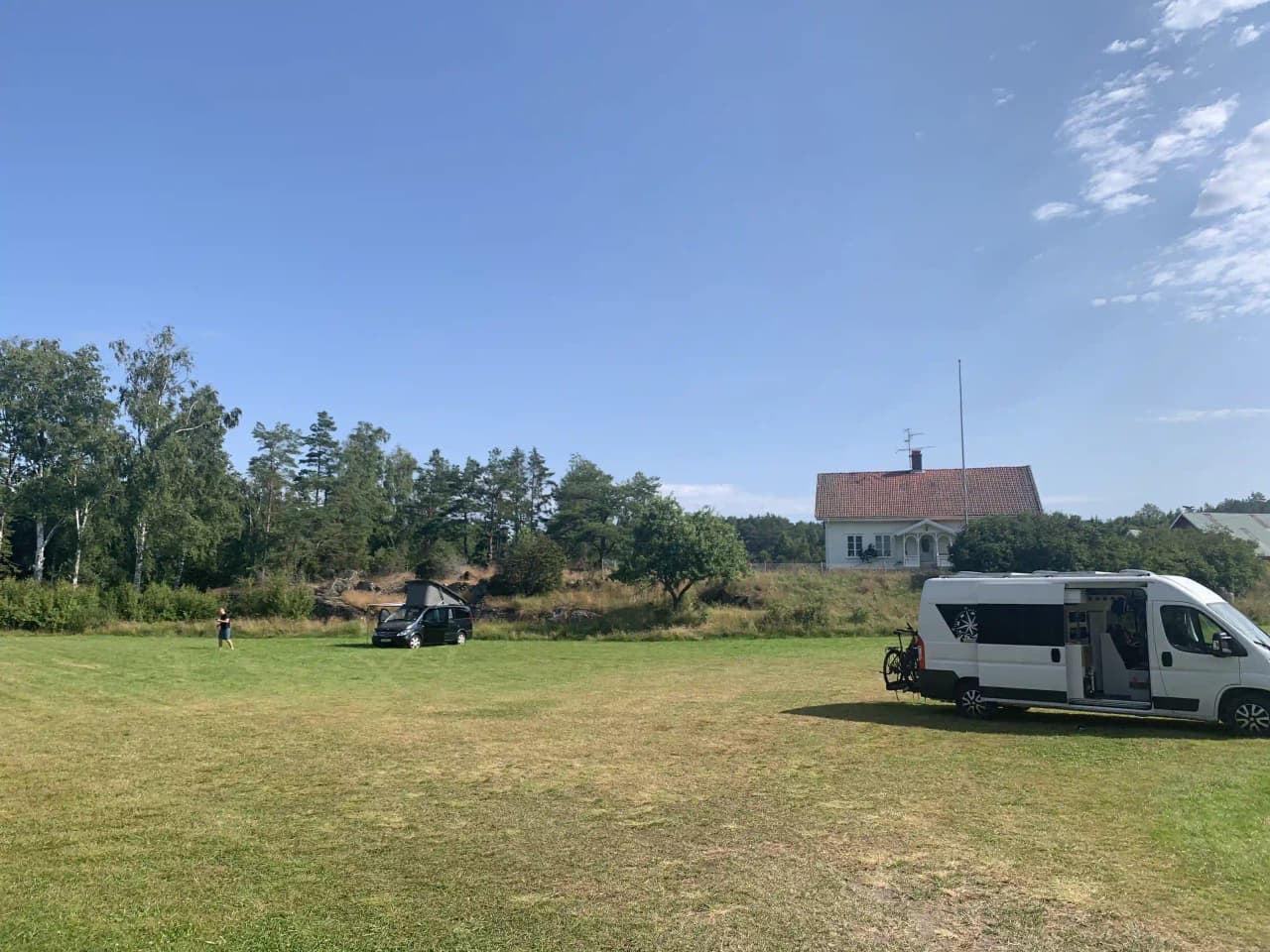 En husbil parkerad på en grön gräsmatta vid Lagunen Camping & Stugor, med ett somrigt och naturnära landskap i bakgrunden.