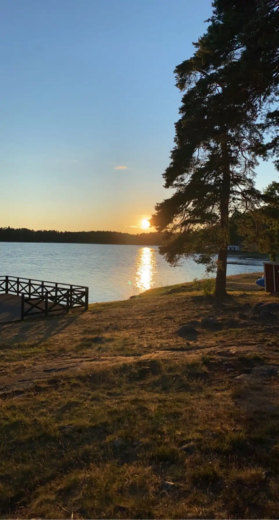 En avkopplande vy över Gudingebadet vid skymningen, med stilla vatten som sträcker sig mot horisonten under en färgglad kvällshimmel.