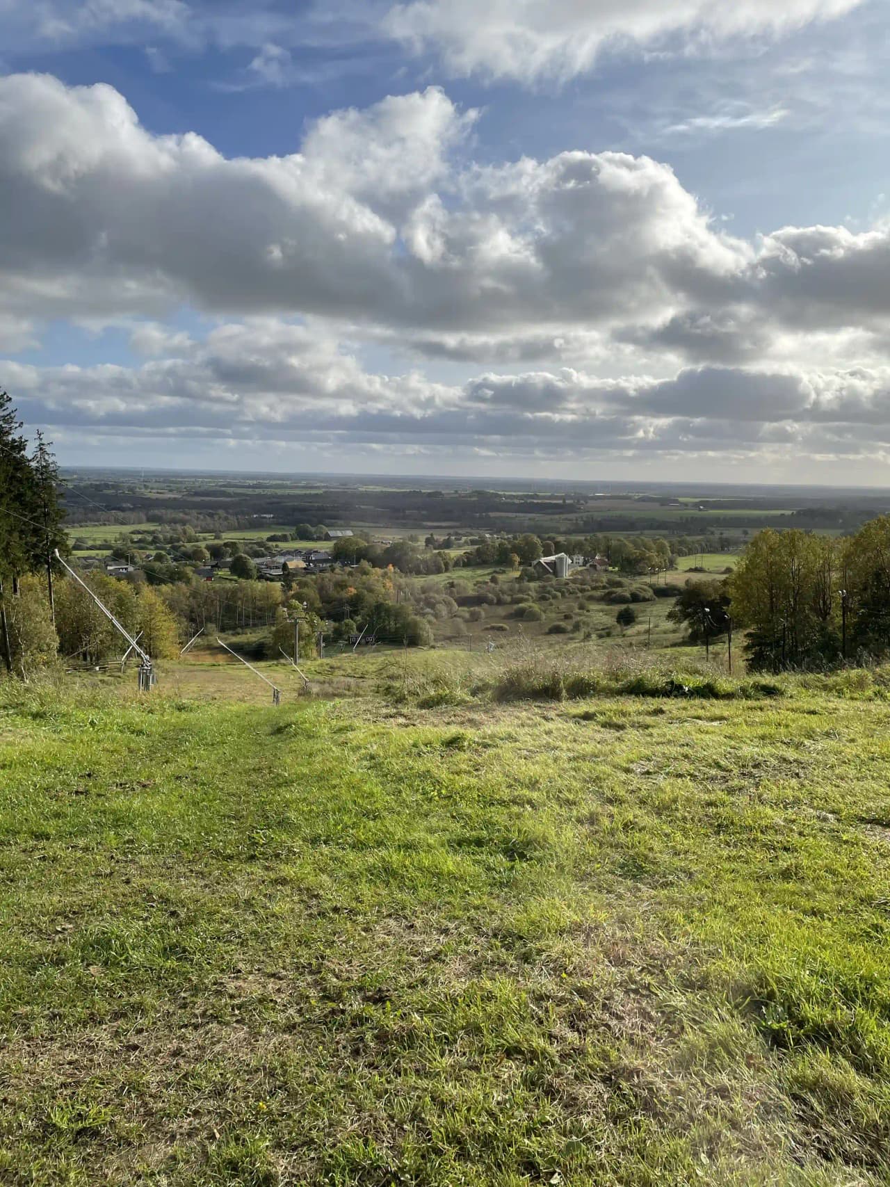 En dagtidsscen vid Mösseberg Camping med blå himmel, moln, grön gräsyta och omgivande växtlighet som skapar en naturskön atmosfär.