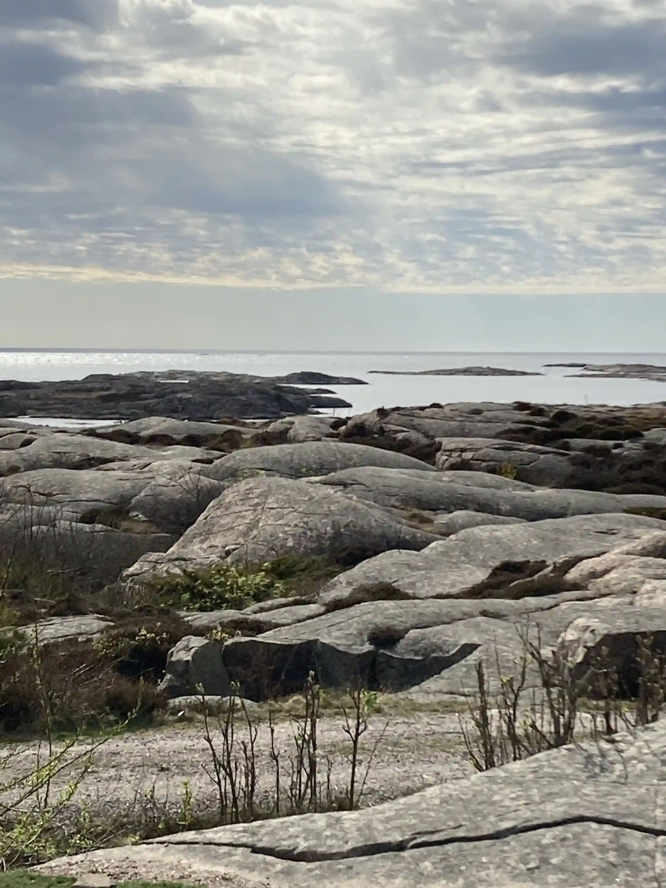 En stenig kustlinje vid Sotenäs Camping, med havet i bakgrunden och gråa klippformationer som sträcker sig mot horisonten.