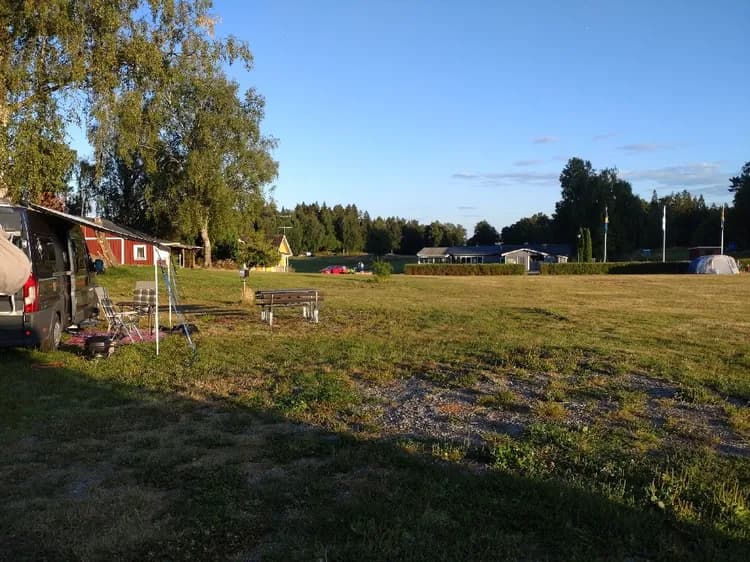 En grön campingplats vid Farstanäs Camping & Havsbad med tält uppställda på gräsmattan och angränsande ängar, omgiven av öppna ytor som passar för rekreation.