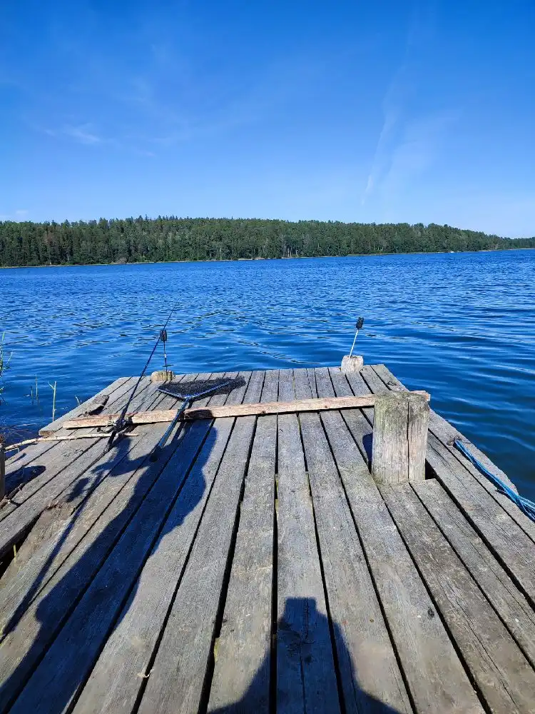 En träbrygga sträcker sig ut i det blå vattnet vid Farstanäs camping & havsbad, med en rogivande utsikt över sjön eller havet.